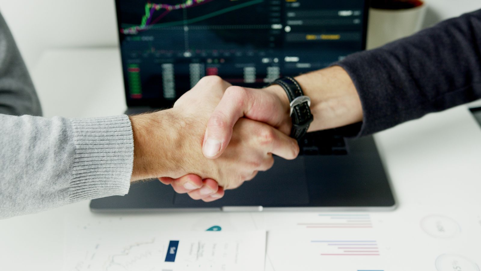 Two people shaking hands over a desk